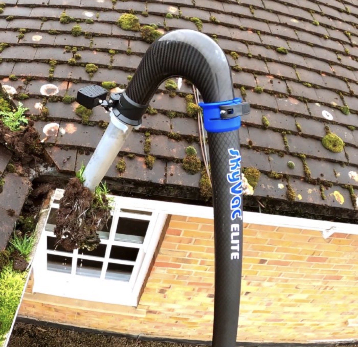 Gutter vacuum clearing moss and debris from roofline gutter