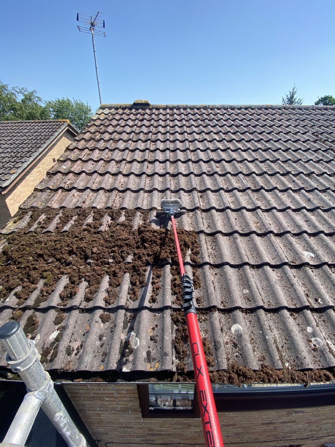 Roof cleaning in progress with professional moss removal equipment